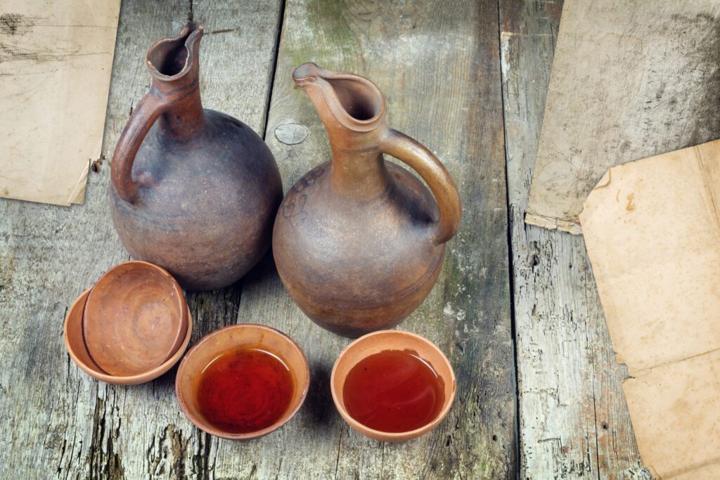 A wine jug and set of clay cups on the wooden table